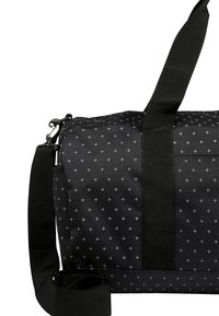SAC DE SPORT NOIR avec un motif de petits croisements blancs, une bandoulière noire réglable, et deux poignées sur un fond blanc.