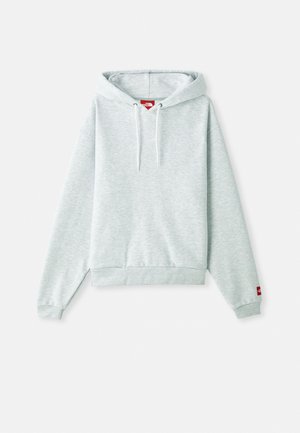 Svijetlosiva dukserica s kengurskim džepom, podesivim vezicama na kapuljači, rebrastim manžetama i malim crvenim logotipom na lijevom rukavu.