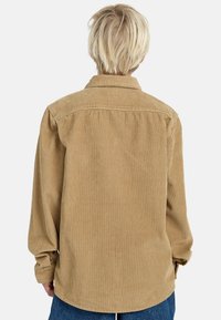 Camicia in velluto a coste marrone con colletto, maniche lunghe e dettaglio del porta spalla sul retro, caratterizzata da una texture a coste verticali e una vestibilità morbida.