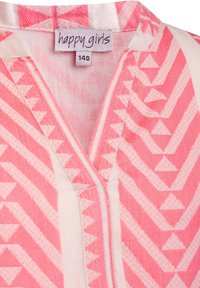 Růžová vzorovaná halenka s geometrickým motivem trojúhelníků, výstřihem do V a štítkem s nápisem "happy girls" a velikostí 140.