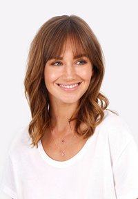 Rosaguld lagdelte halskæder med runde vedhæng båret over en hvid t-shirt. Modellen har skulderlangt, bølget brunt hår med pandehår.