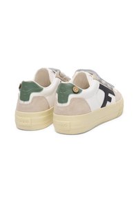 Baskets blanches et beiges avec des accents en daim, semelle en caoutchouc, patch au talon vert et une sangle Velcro. Nom de la marque "Faguo" au talon.