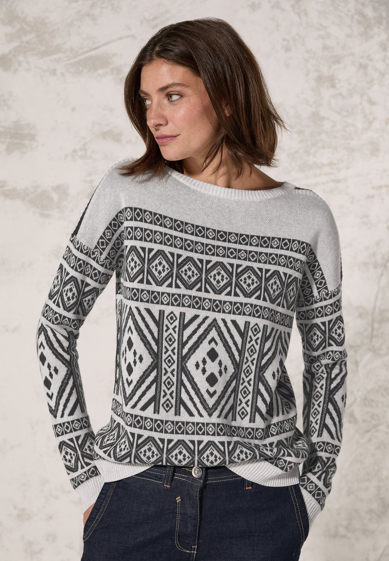 Pull gris avec des motifs géométriques noirs, col rond, manches longues et poignets côtelés. Tissu tricoté doux et coupe décontractée.