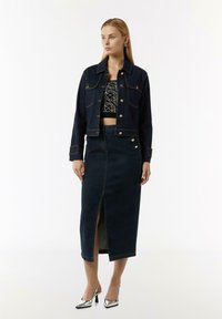 Zestaw kurtek i spódnicy dżinsowej w ciemnoniebieskim kolorze. Kurtka ma guziki i kieszenie; spódnica ma rozcięcie z przodu oraz dekoracyjne guziki z boku.