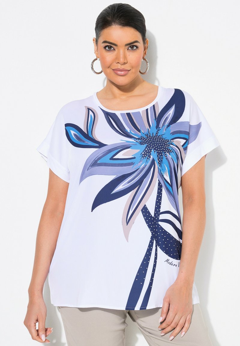 Top corto de manga corta blanco con un gran patrón floral azul que incluye detalles intrincados, con acentos en azul oscuro y elementos punteados.