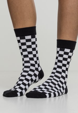 Schwarz-weiße Karomuster-Socken aus weichem Stoff, mit kontrastierenden gerippten Bündchen und einem runden Zehenbereich. Das Karomuster zieht sich über die gesamte Socke.