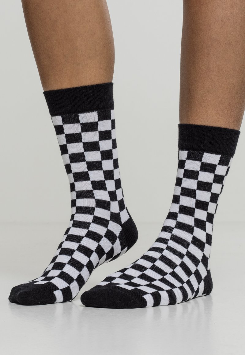 Svartvita rutiga strumpor i mjukt tyg, med kontrasterande ribbade muddar och en rund tådesign. Rutmönstret täcker hela strumpan.