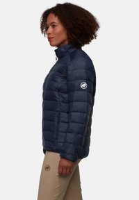 Giubbotto imbottito blu navy con trapuntatura verticale, collo alto, tasca frontale con zip e patch logo sul braccio sinistro.
