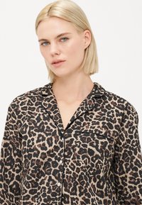 Pysjamaskjorte med leopardmønster i lett materiale har klassisk krage, knappelukking og lomme på venstre side.