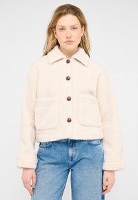 Cream-colored, fuzzy jacket with a collar, button closure, and two front pockets. Features brown buttons and a cropped design.