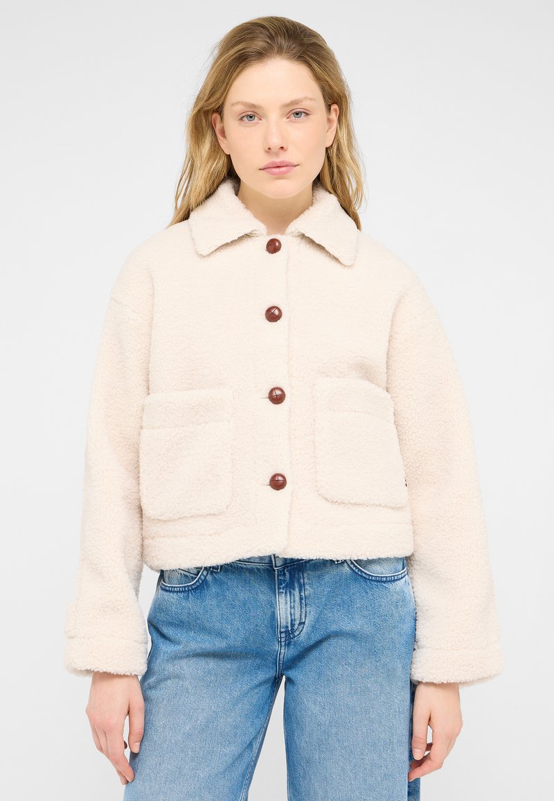 Cream-colored, fuzzy jacket with a collar, button closure, and two front pockets. Features brown buttons and a cropped design.