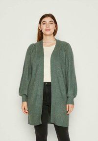 Cardigã verde de malha, com mangas bufantes longas e design aberto na frente. Feito de material suave, possui punhos canelados e um corte descontraído.