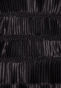 Tessuto nero plissettato con pieghe verticali, texture liscia e motivo uniforme, creando un aspetto strutturato in tutto il tessuto.