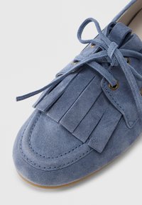 Scarpa in suede blu con punta arrotondata, caratterizzata da un design con frange e chiusura con lacci. Rifinita con occhielli dorati e suola cucita.