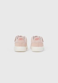 Šviesiai rožiniai zomšiniai sportiniai bateliai su balta guminė pado danga, pasižymintys siuvinėtu dizainu ir reljefiniu logotipu ant kulno. Minimalistinė ir apvali forma.