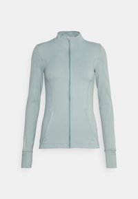 Světlomodrá atletická bunda na zip s dlouhými rukávy, dvěma předními kapsami, plochými švy a drobnými perforovanými detaily na rukávech.