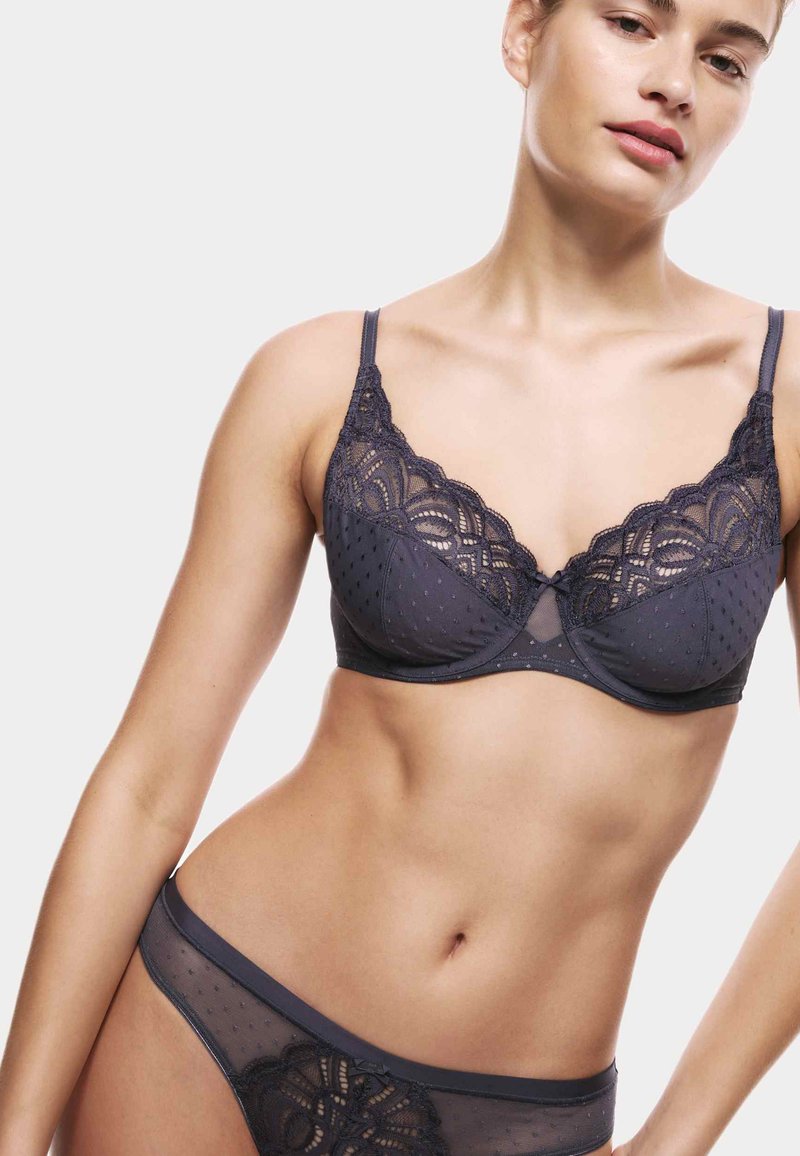 Dunkelgrauer Spitzen-BH mit gewellten Kanten, Pünktchenmuster und verstellbaren Trägern, kombiniert mit einem passendem tief geschnittenen Slip mit Spitze.