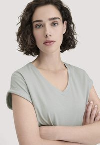 Lichtgroene, kortere mouw V-hals t-shirt met een zachte textuur en opgerolde mouwen, ontworpen voor een relaxed fit. Subtiele kleur en een simpele stijl.