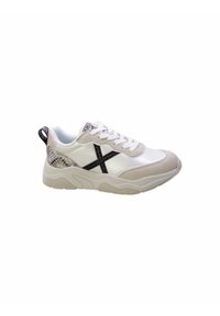 Baskets blanches avec des accents en daim beige, des coutures décoratives noires en forme de "X", un panneau latéral texturé et une semelle en caoutchouc.