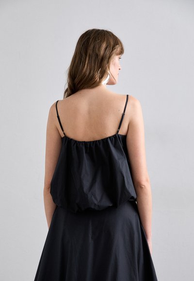 Haut sans manches noir avec un design froncé, en tissu léger, doté de fines bretelles ajustables et d'une coupe ample.