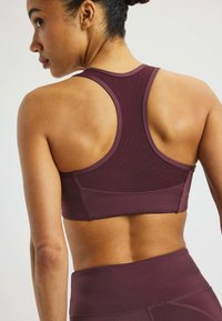 Bralette burgundi z dizajnom racerback in teksturirano tkanino. Ima šive za podporo in oprijet slog.