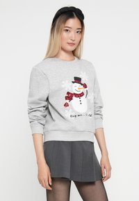 Szary sweatshirt z błyszczącym wzorem bałwanka i napisem, w połączeniu z plisowaną szarą spódnicą. Gładka faktura z dopasowanymi mankietami i dołem.
