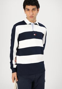 Marineblå og hvite stripete langermet polo-skjorte med krage, med en liten logo-patch og knappestolpe. Laget av bomull, med en avslappet passform.