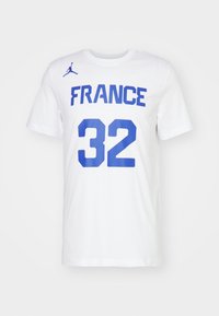 Biały bawełniany T-shirt z niebieskim napisem "FRANCE" i numerem "32" na przodzie, oraz małym niebieskim logo Jumpman na lewym ramieniu.