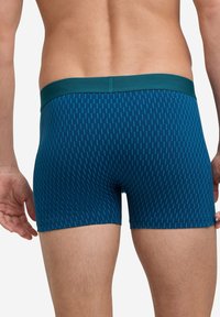 Blaue gemusterte Boxershorts mit einem einfarbigen tealfarbenen Bund, die vertikale Linien und eine enganliegende Passform aufweisen, aus weichem Stretchmaterial gefertigt.