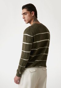 Olivgrüner gestreifter Pullover mit weißen horizontalen Streifen, Rundhalsausschnitt und langen Ärmeln; strukturiertes Material mit gerippten Bündchen. Lässige Passform.