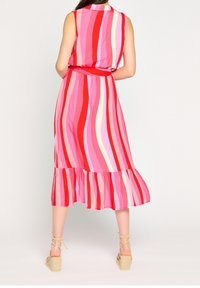 Różowo-czerwona sukienka bez rękawów w paski z rozkloszowanym dołem, talią ściągniętą paskiem oraz wykonana z lekkiego materiału.