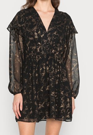 Czarna sukienka ze złotym wzorem w folii, przezroczystymi długimi rękawami, dekoltem w serek, zapinana z przodu na guziki oraz z falbanką na ramionach.