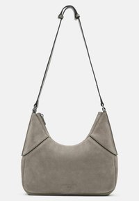 Grijze suède schoudertas met een gebogen vorm, voorzien van een zwarte verstelbare schouderband, scherpe naden en een ritssluiting aan de bovenkant.