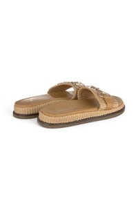 Sandales brunes à enfiler avec une tige en jute tressé, deux lanières en cuir et une semelle en caoutchouc plate. Présente des accents métalliques sur les lanières.