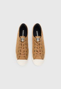 Brązowe zamszowe niskie trampki z beżowym gumowym noskiem, płaskimi sznurówkami i czarną wkładką z logo "CONVERSE".