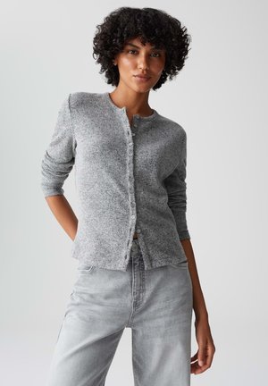Grauer gestrickter Cardigan mit rundem Halsausschnitt, Knopfverschluss und langen Ärmeln. Über hellgrauen Jeans getragen. Glatte Textur.