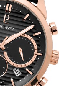 Czarny zegarek chronograf z fakturowaną tarczą, różowozłotymi akcentami oraz trzema małymi tarczkami. Posiada okno daty oraz wyraźną koronkę.