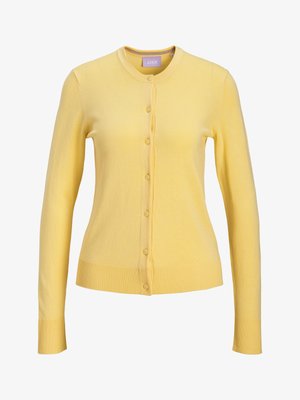 Geltonas ilgomis rankovėmis megztinis su sagomis, apvalia iškirpte ir gofruotomis rankogaliais bei apačia.