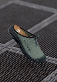 Grønn slip-on sko med et teksturert stoffoverdel, gummisåle og mønsterdesign. Har et logo på siden og polstret innersåle.
