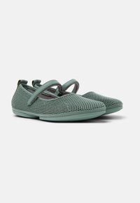 Zapatos slip-on de malla verde con cintas cruzadas, punteras redondeadas y suelas texturizadas, que cuentan con un material transpirable y un diseño minimalista.