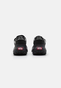 Scarpe da trekking robuste in nero e grigio con suola spessa e texturizzata. Presentano cinturini regolabili e il marchio "MTE" sul tallone.