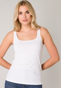 Witte tanktop van glad, lichtgewicht materiaal. Heeft een vierkante halslijn en dunne banden, sluit nauw aan op het lichaam.
