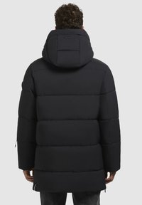 Sort dunjakke med hætte, der har et quiltet design, lange ærmer og en afslappet pasform. Ryggen har et lille rum.