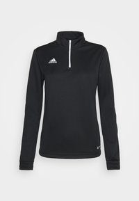 Polo de sport Adidas noir à manches longues avec demi-fermeture éclair blanche et col montant, logo à l'avant côté gauche de la poitrine.