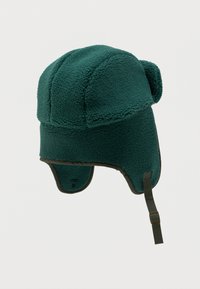 Zelená čiapka typu trapper s fleecovou podšívkou, s ušnými chlopňami, zaoblenou vrchnou časťou a podbradníkom. Má jemnú textúru a kontrastný lem.