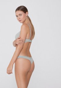 Hellgraues Dessous-Set mit einem Bralette mit verstellbaren Trägern und einem String-Tanga, gefertigt aus weichem, glattem Stoff.