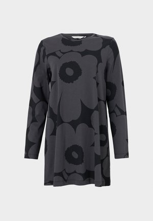 Tumšā pelēkā džersija auduma tunika ar garām piedurknēm, kurai ir liels melns ziedu raksts. Apaļa kakla izgriezuma forma un brīva A līnijas siluets.