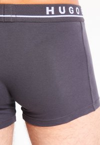 Dunkelgraue Boxer-Brief aus glattem Stoff mit passgenauer Passform. Verfügt über einen weißen, gebrandeten Bund und eine kurze Länge.