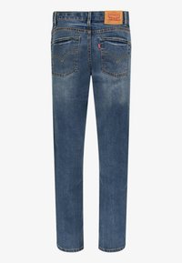 Jeans de mezclilla azul con corte recto, ligero desvanecimiento y dos bolsillos traseros con un logo bordado. La cinturilla tiene un parche de cuero con la marca.