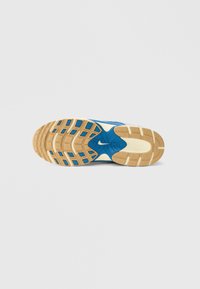 Εξωτερική σόλα αθλητικού παπουτσιού Nike σε καφέ, μπλε και κρεμ αποχρώσεις. Διαθέτει υφή από καουτσούκ για πρόσφυση, με εξαγωνικά σχέδια και λεπτομέρεια με το λογότυπο.